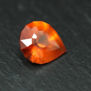 Macro-opname van een 5.3 karaat oranje spessartien granaat in Aqua Drop slijpvorm op zwarte leisteen