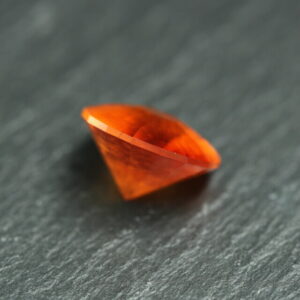 Macro-opname van een 5.3 karaat oranje spessartien granaat in Aqua Drop slijpvorm op zwarte leisteen