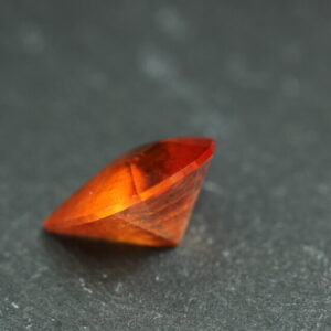 Macro-opname van een 5.3 karaat oranje spessartien granaat in Aqua Drop slijpvorm op zwarte leisteen