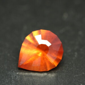 Macro-opname van een 5.3 karaat oranje spessartien granaat in Aqua Drop slijpvorm op zwarte leisteen