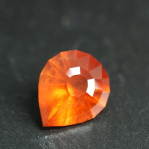 Macro-opname van een 5.3 karaat oranje spessartien granaat in Aqua Drop slijpvorm op zwarte leisteen